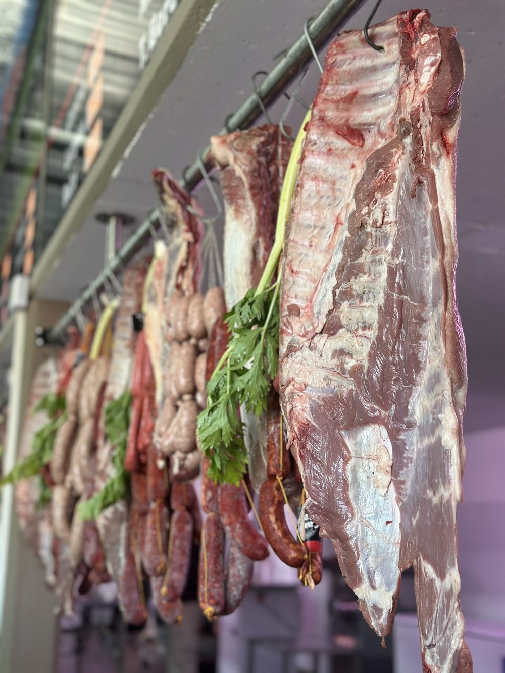 Medias reses, chorizos y achuras colgados en el mostrador de El Noba